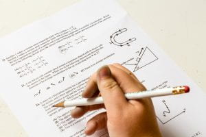 Hand with pencil works on math test with geometry signals