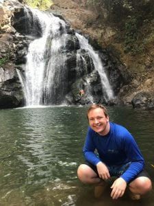 Nathan posing in front of a waterfall