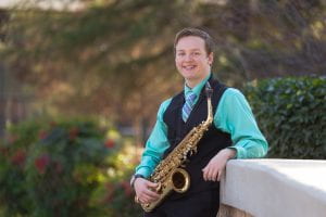 Nathan leans suavely against a Stanislaus bridge with Saxophone in hand